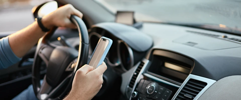 Mann mit Handy am Steuer