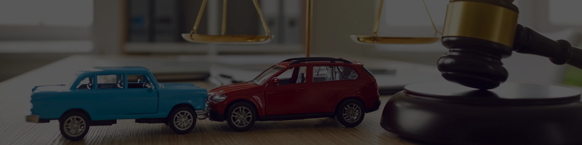 Zwei Spielzeugautos, eine Justitia Waage und ein Richterhammer