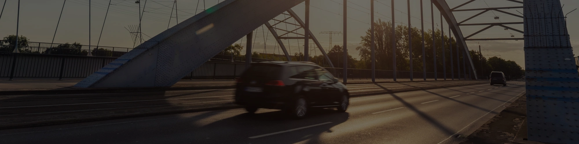 Auto überfährt bei Sonnenaufgang eine Brücke