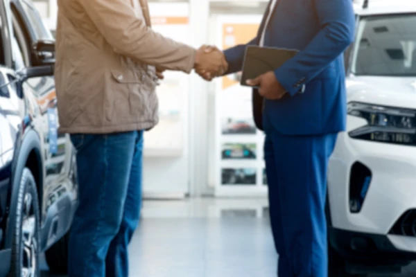 Autohändler und Käufer schütteln Hände