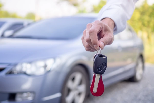 Fahrverbot trotz neuem Job? Eine Hand hält einen Autoschlüssel vor einem Auto