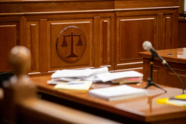 Gericht vergisst Verjährung Richterbank in einem Gerichtssaal mit Justitia-Symbol, Mikrofon und Aktenstapel auf dem Tisch