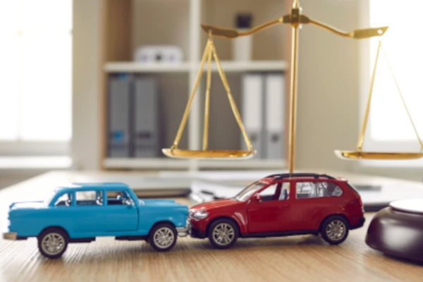 Zwei Spielzeugautos, eine Justitia Waage und ein Richterhammer