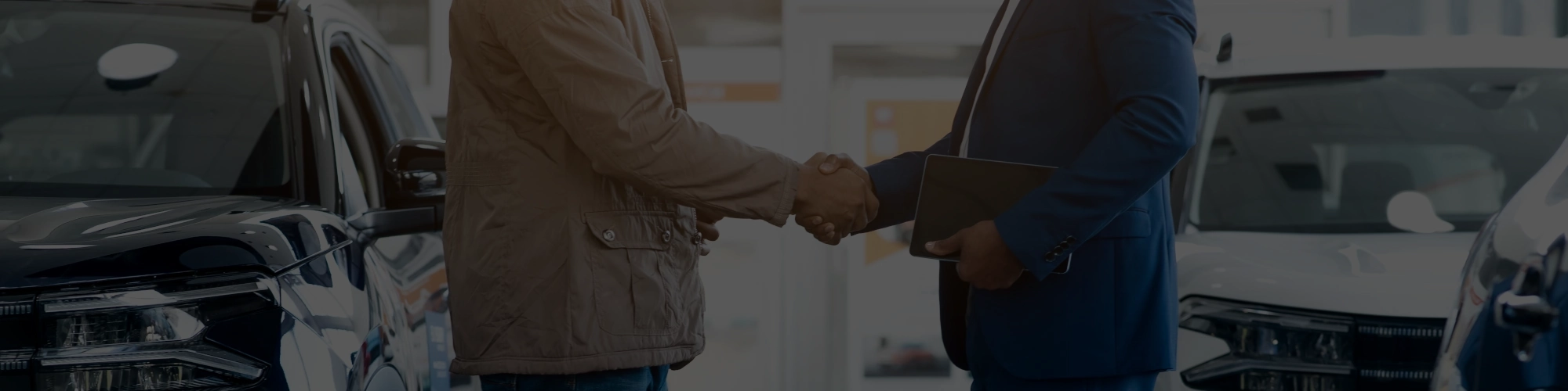 Autohändler und Käufer schütteln Hände